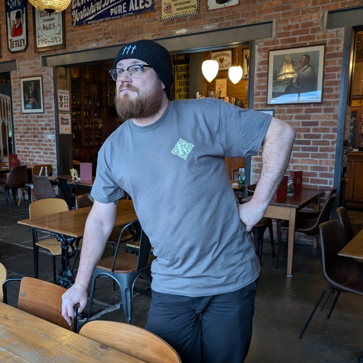 Man Leaning On Chair Wearing Grey Kirkstall T-Shirt